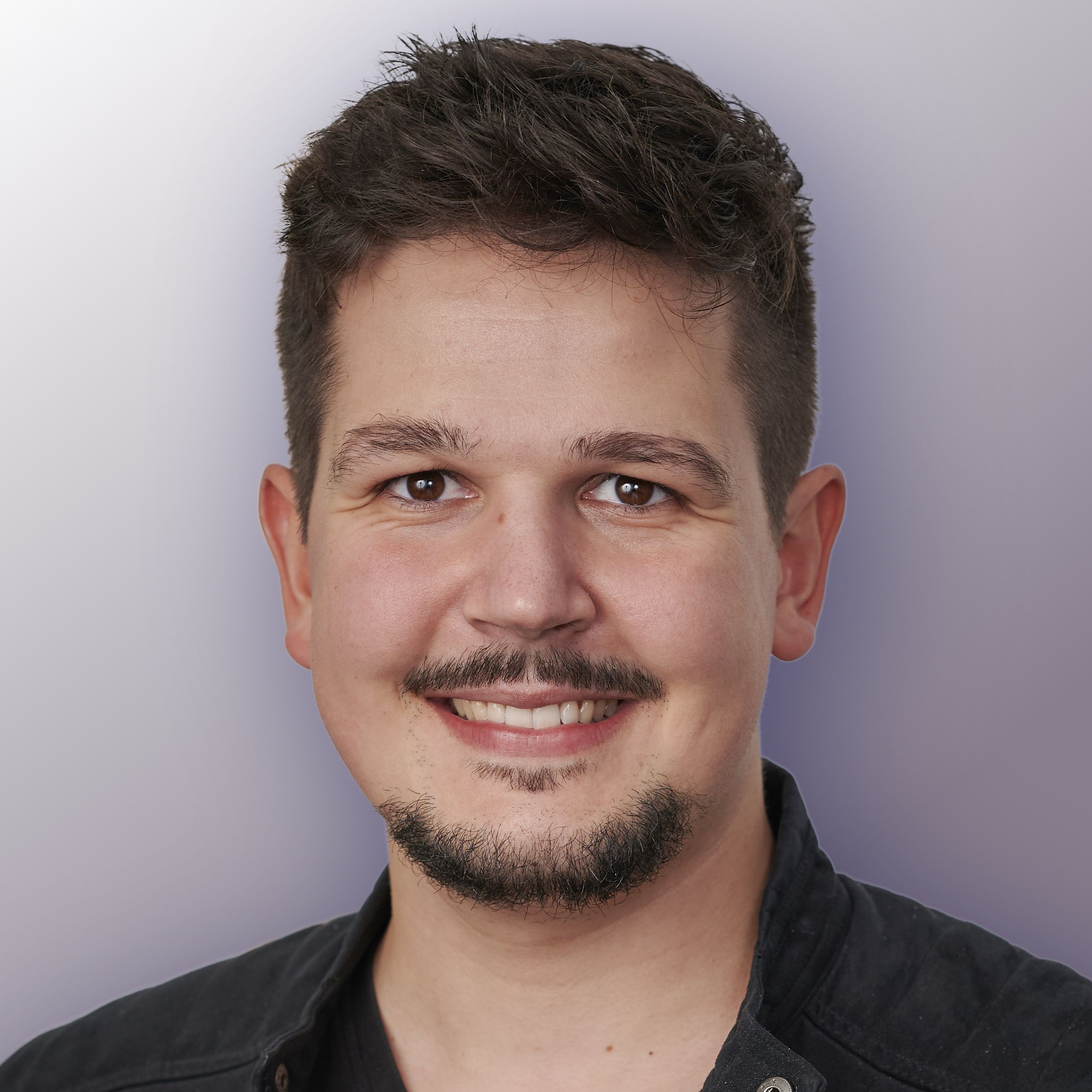 Tobias Knab Porträt Mann mit dunklem Haar und Bart lächelnd schwarzes Hemd